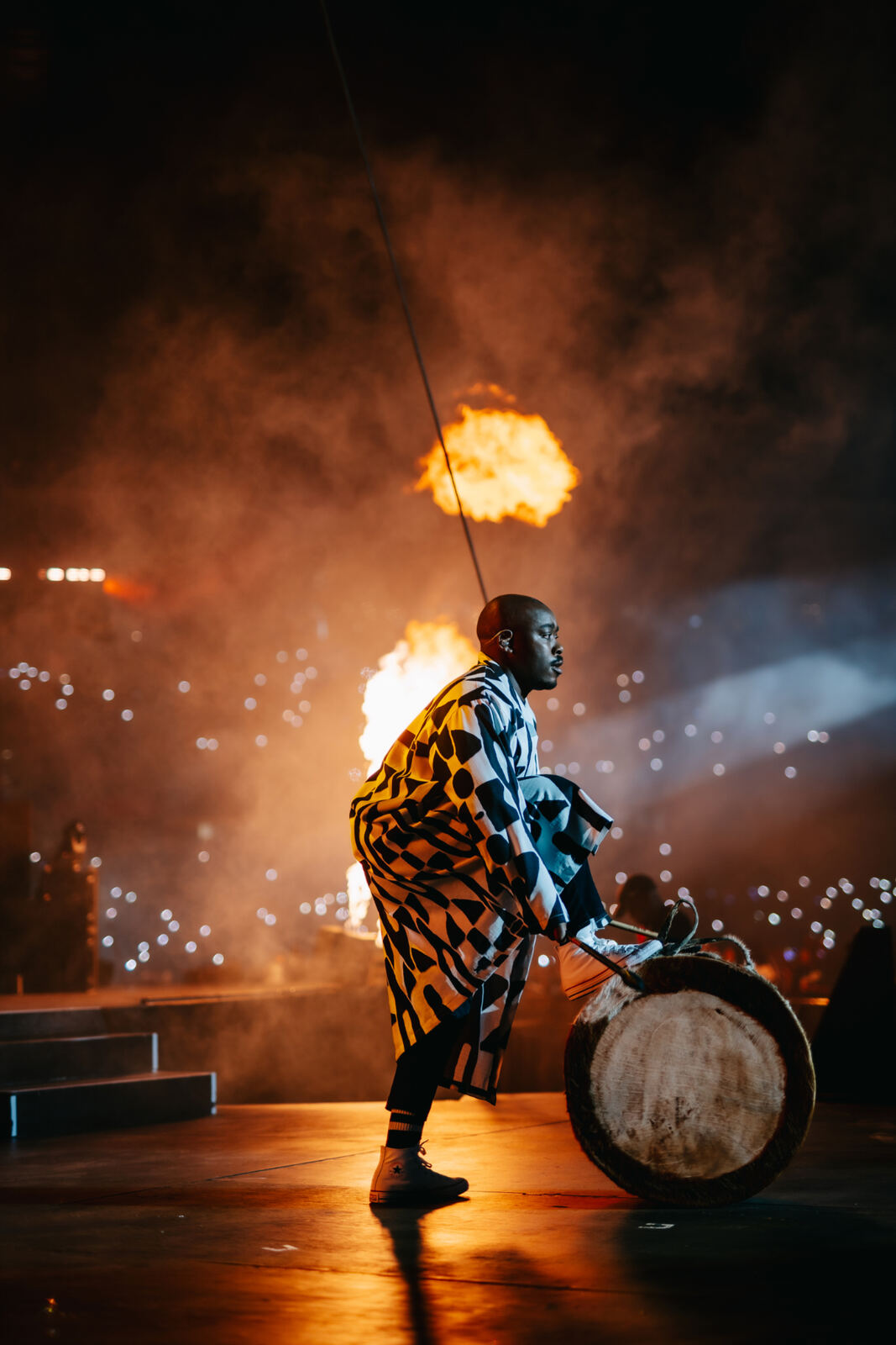 Traditional drummer on stage framed by flames