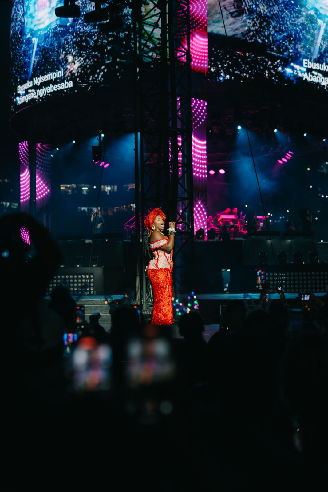 Vocalist in red performing under stadium lights